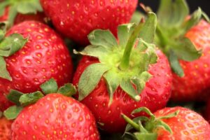 Vibrant close-up of fresh red strawberries with green leaves, highlighting natural texture and color.